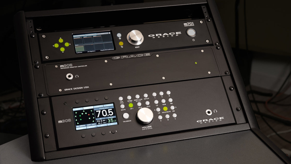 A Grace Design m908 monitor controller and its desktop remote fitted in an equipment rack in a dim room