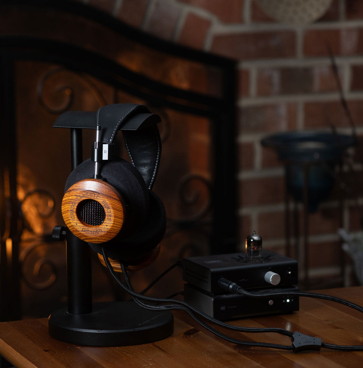 Grado GS3000 on a headphone stand beside a valve headphone amplifier, in front of a fireplace