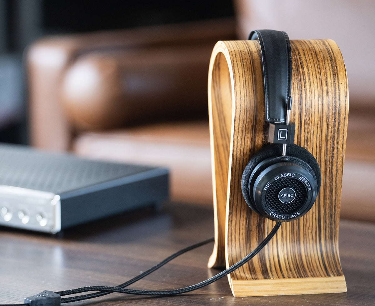 Grado SR80 resting on a wooden headphone stand on a table