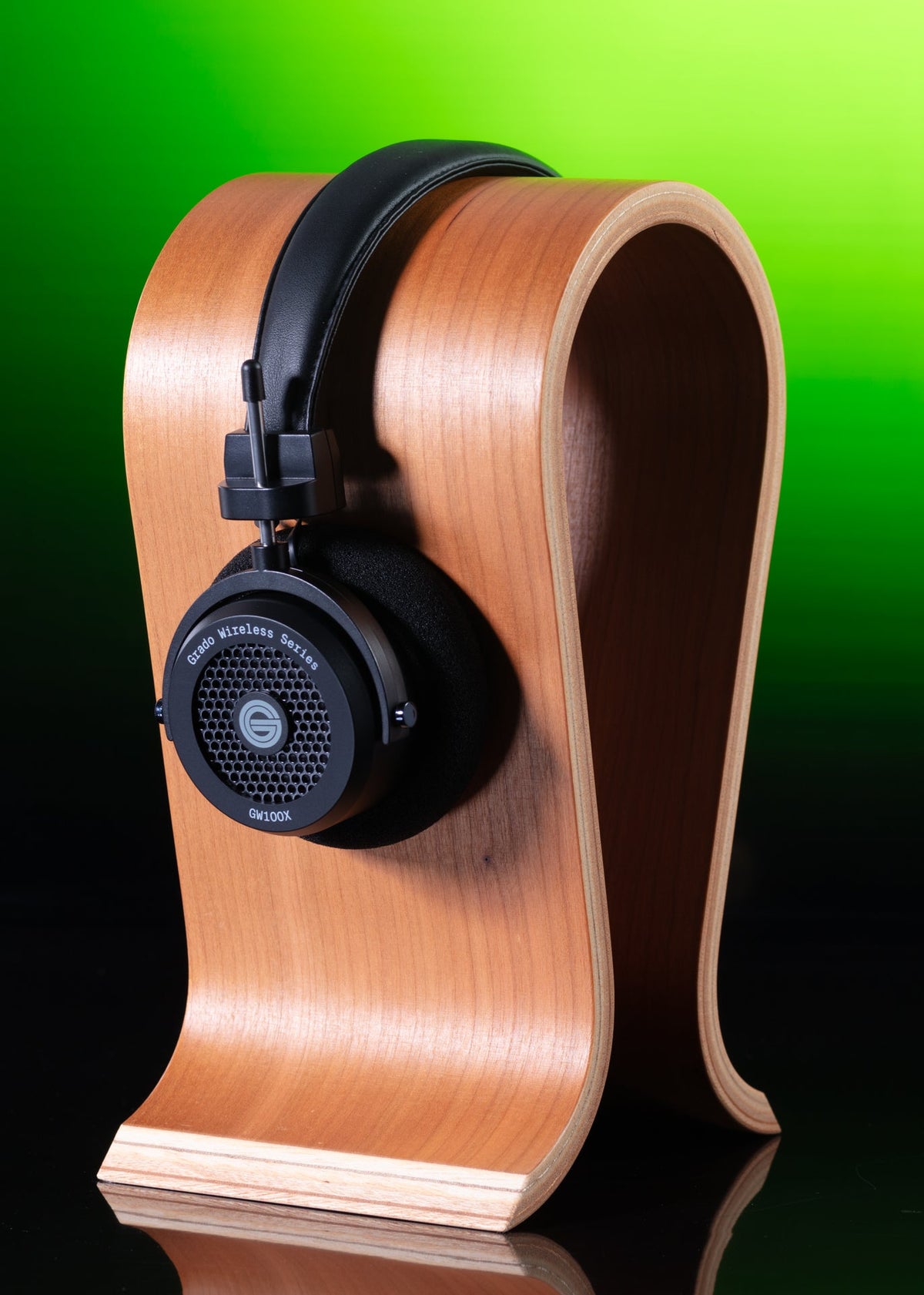 Grado GW100x on a curved wooden headphone stand against a green backdrop