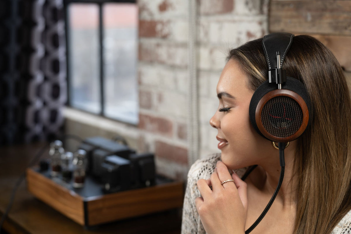 Grado Signature S950 worn by a listener, seen in profile, with a valve amplifier behind her