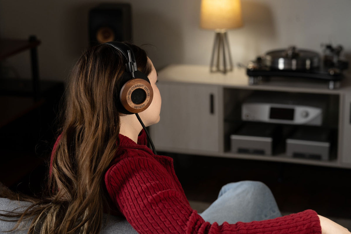 Grado GS1000 worn by a listener on a sofa, with a turntable and hi-fi rack across the room