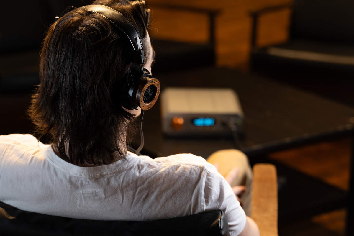 Grado RS1 worn by a listener seated in front of a headphone amplifier