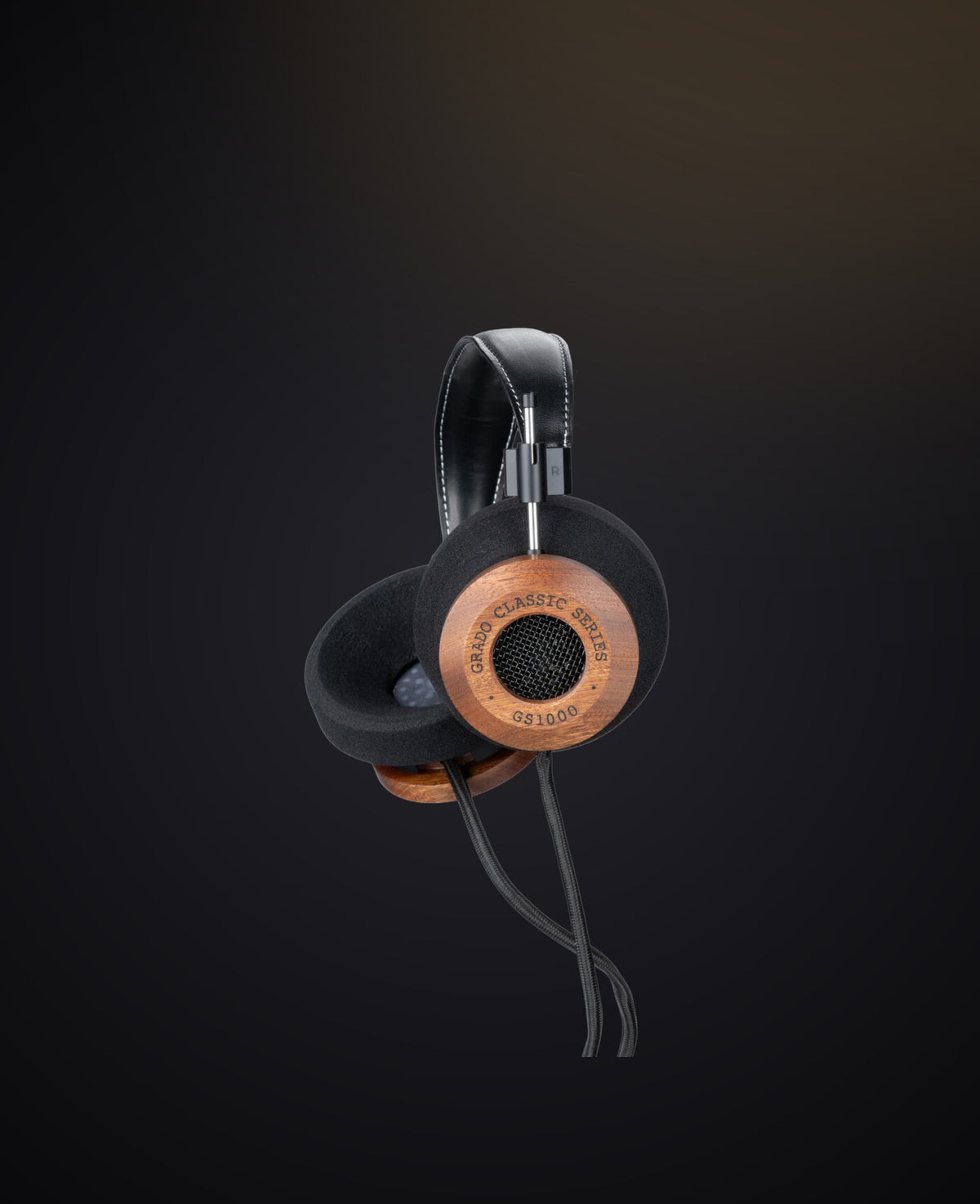 A mahogany headphone lit warm against a dark ground