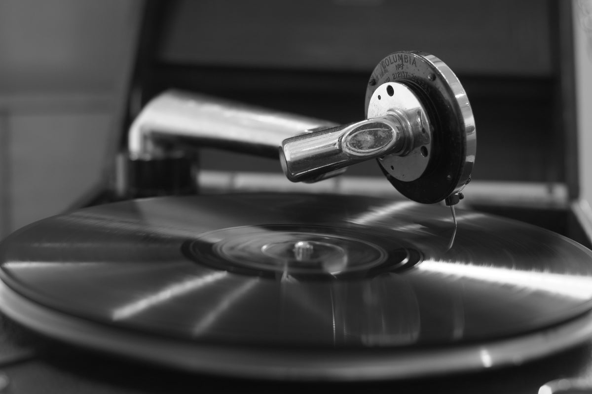 A record spinning on an old wind-up gramophone, its Columbia soundbox and needle in the groove, in black and white