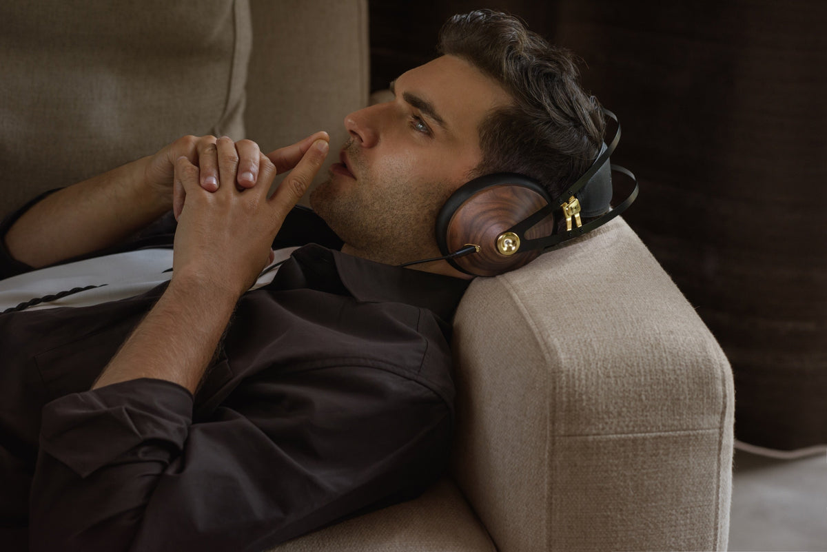 A man lying back on a cushion, hands clasped at his chin, eyes shut, 99 Classics on, in a dim brick-walled room. Very warm, very low key, nothing else in the frame.