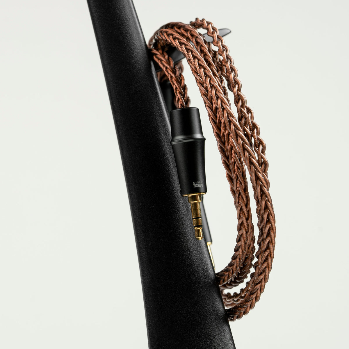 Meze Audio Manta Headphone Stand, with a coiled headphone cable hung on its column