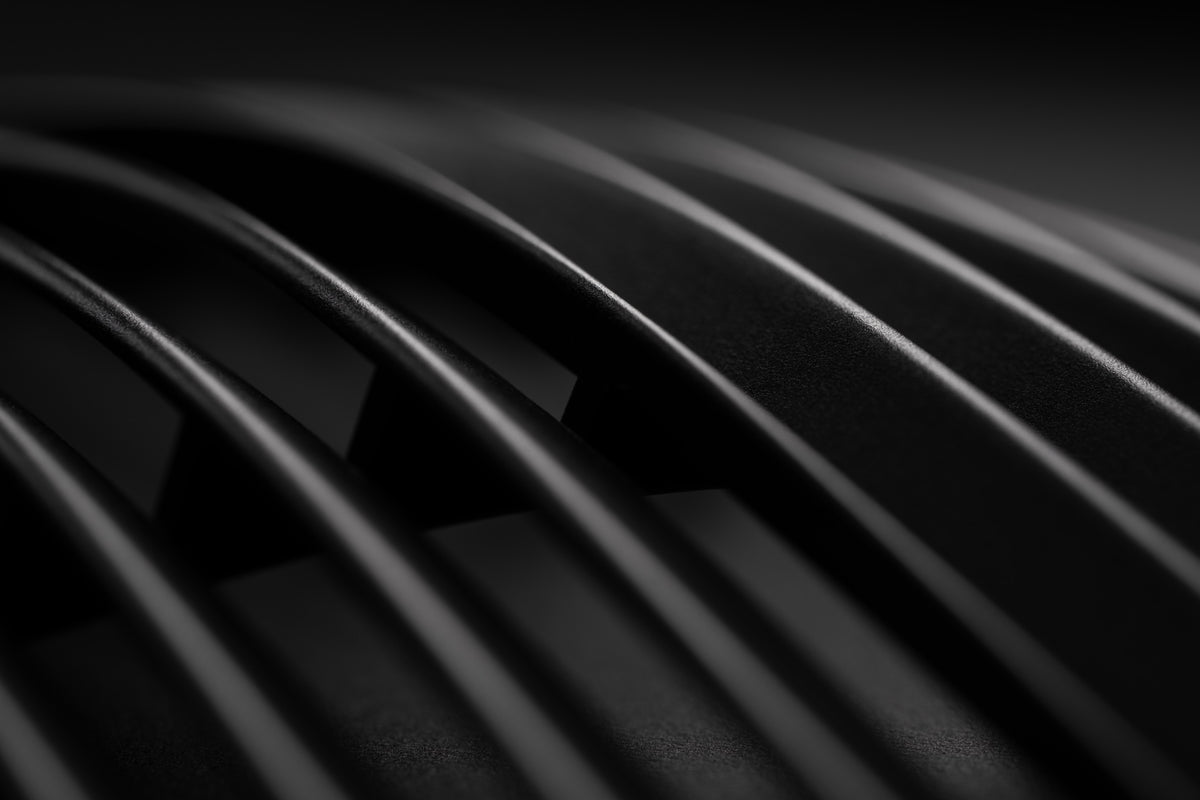 Close up of the black ribbed cup of a Meze headphone, lit low from one side