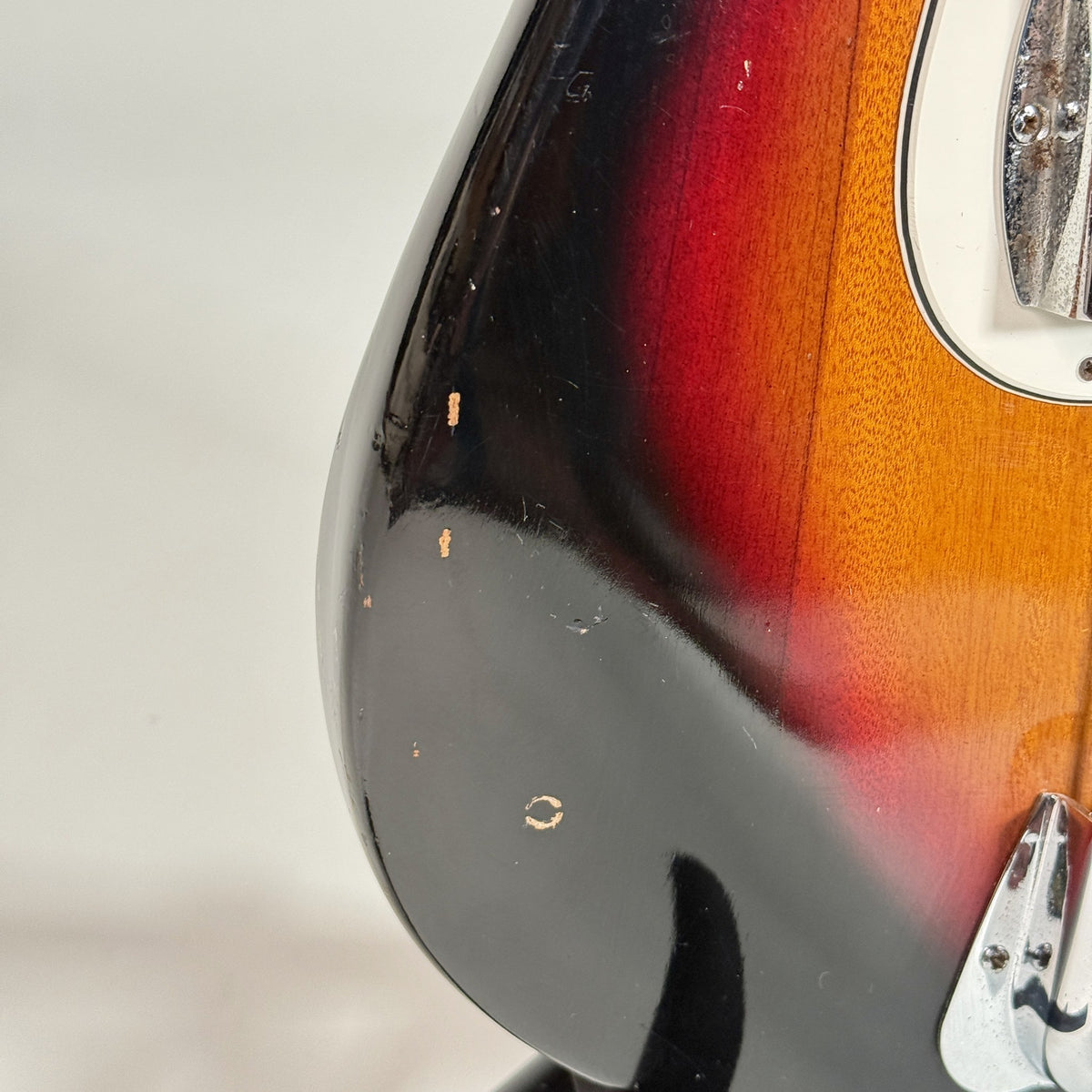 Used unbranded P-bass style bass in sunburst, close up of chips on the lower bout