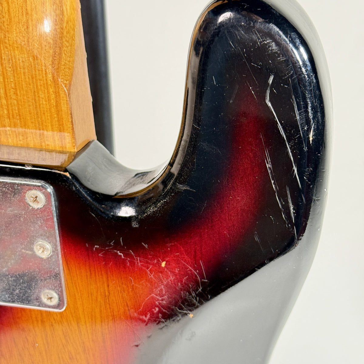Used unbranded P-bass style bass in sunburst, close up of wear at the neck heel