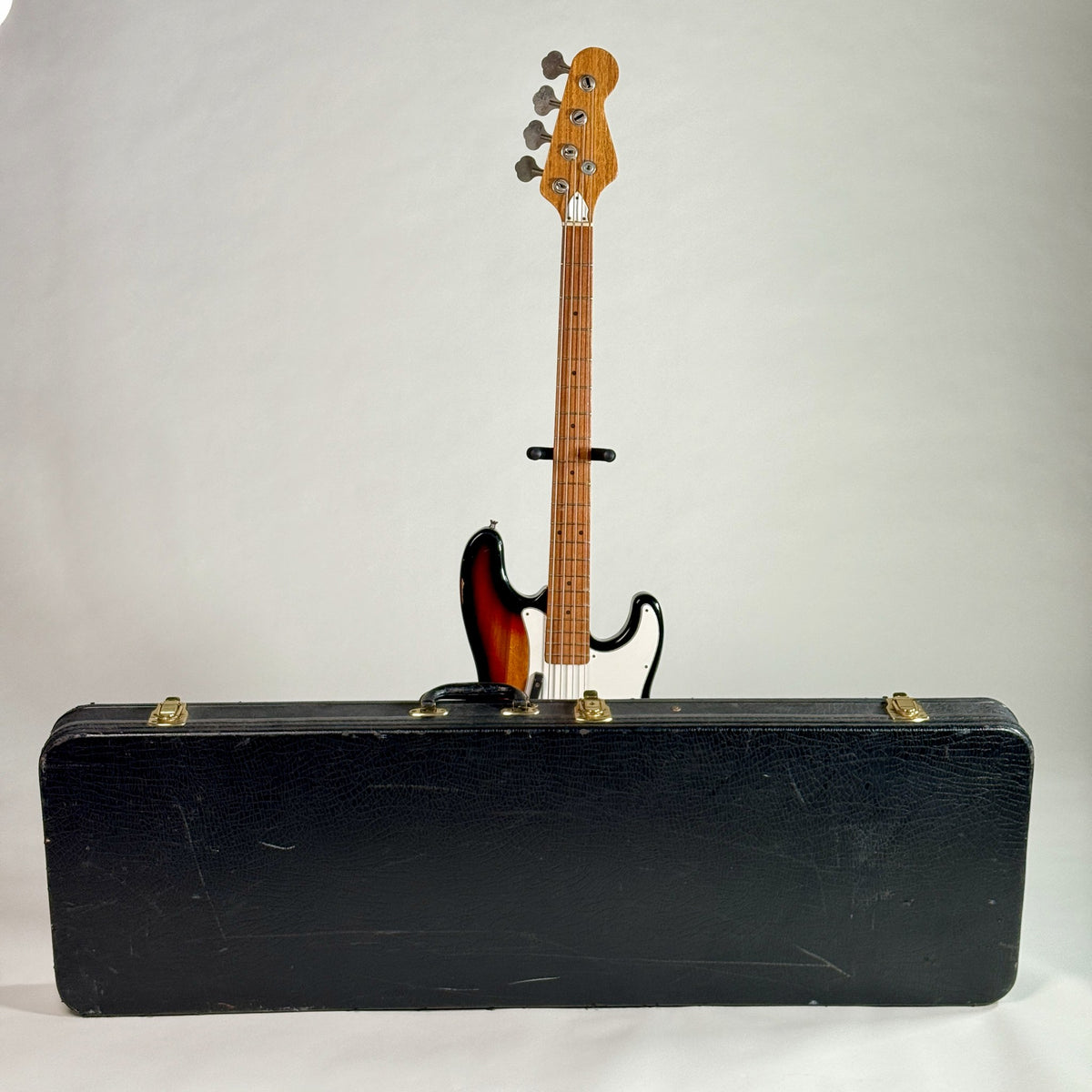 Used unbranded P-bass style bass in sunburst, standing behind its hardshell case